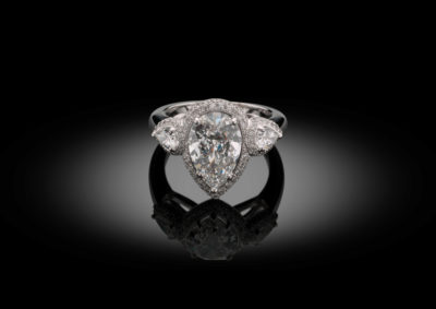 Exceptional trilogy ring with pear shaped diamonds, finished with a double diamond entourage.